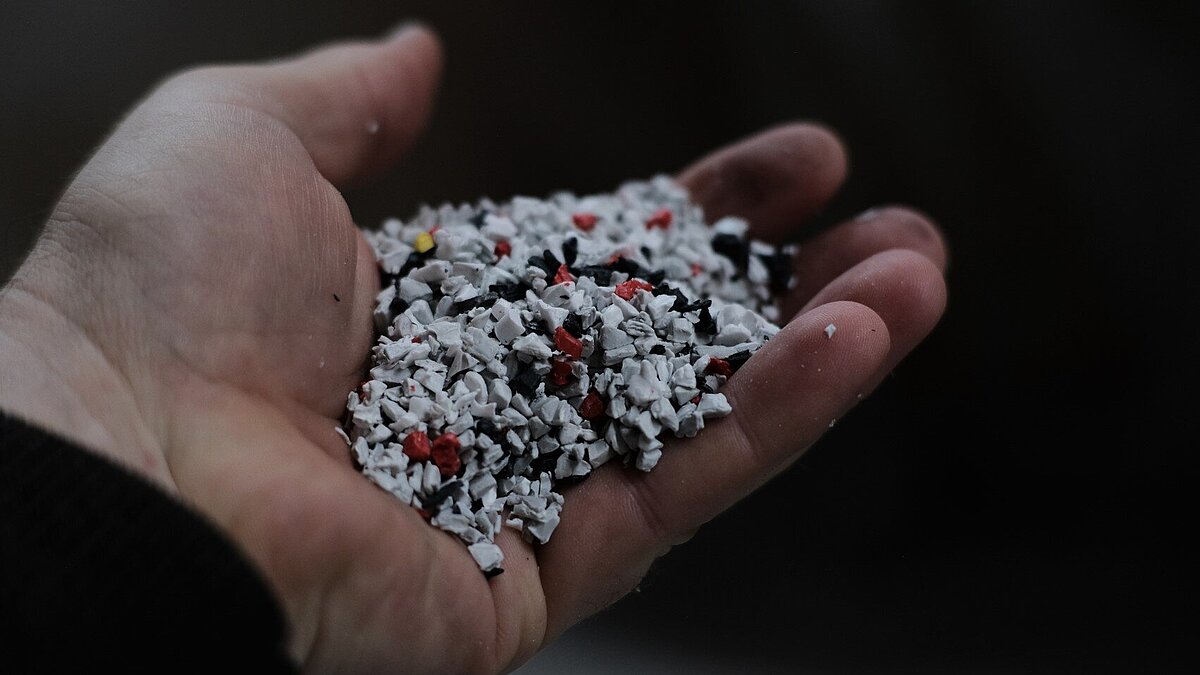 Sortenreine innerbetriebliche Materialrückgewinnung mit PIR & PCR bei metak Ausgestreckte Hand, auf der Kunststoffgranulat liegt